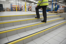 Anti-slip aluminium stair nosing with Yellow PVC insert — installed on UK staircase with person using the stairs
