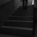 Tile-in aluminium step edging in Black — installed on tiled UK staircase with person using the stairs
