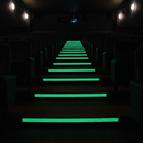 Photoluminescent anti-slip tape on cinema auditorium stair nosings — green glow in darkness
