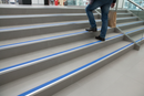 Anti-slip aluminium stair nosing with Blue PVC insert — installed on UK staircase with person using the stairs