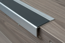 Close-up of anti-slip aluminium stair nosing ramp profile showing permanently bonded grey PVC insert at step nose