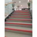 Red silicon carbide anti-slip tape on commercial stair nosings — ISO 7010 fire safety red