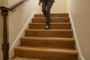uPVC wood effect stair nosing in Gold Walnut — real-life installation on UK staircase with person using the stairs