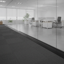 Black self-adhesive PVC floor strip in contemporary UK office between carpet tiles and concrete flooring