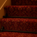 Black stair rods securing burgundy runner carpet on traditional British staircase