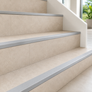 Silver aluminium straight edge stair nosings fitted to beige tiled steps in a bright interior