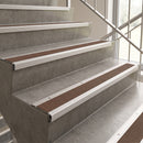 Brown textured stair grips installed on concrete stairs with white metal rails and a glass railing.
