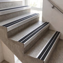Concrete stair treads with black grip strips installed on a modern staircase indoors.