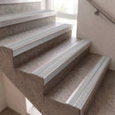 Close-up of concrete stairs with silver metal handrails and steps, photographed indoors near a window.