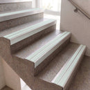 Light green non-slip rubber strips installed along the edges of indoor concrete stairs.