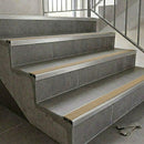Slimline aluminium stair nosings with beige anti-slip inserts on grey tiled staircase