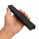 Hand holding a short offcut of black carborundum insert, showing the grit top and ribbed underside