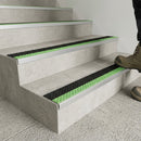 Boot stepping onto pale concrete stairs fitted with black and green insert nosings