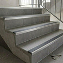 Slimline aluminium stair nosings with black anti-slip inserts on grey tiled staircase