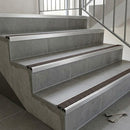 Aluminium tile-in stair nosing with a dark brown anti-slip PVC insert fitted to each tread of a tiled staircase