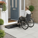 Black rubber threshold ramp helping a wheelchair user cross a raised front door step at a UK home entrance