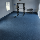 Blue rubber gym flooring roll fitted in a home garage gym with a power rack and dumbbell rack