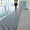 Grey PVC duckboard wet area matting laid poolside next to an indoor swimming pool with a person walking barefoot