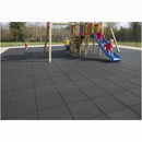 Black interlocking rubber playground safety tiles laid beneath a children's climbing frame and slide in a UK playground