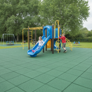 Green interlocking rubber playground safety tiles installed under a blue slide and climbing frame with children playing