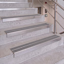 Stainless steel handrails installed on concrete stairs, featuring textured grip strips on each step and a matching handrail along the right side.