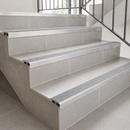 Slimline aluminium stair nosings with grey anti-slip inserts on light grey tiled steps