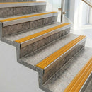 Square front aluminium stair nosings with golden yellow ribbed inserts on pale concrete steps