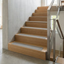 Light grey inserts on oak timber stairs in a concrete-walled stairwell