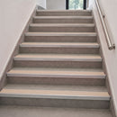A set of modern non-slip stair grips in beige and gray, installed on a staircase with a stainless steel handrail.