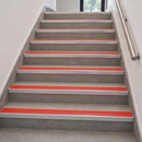 Gray concrete stairs with bright red anti-slip strips and silver metal handrails on both sides.