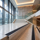 Modern interior staircase with terrazzo-style steps, glass railings, and warm ceiling lighting in a high-rise building.