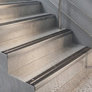 Inox anodised stair nosings with twin black rubber inserts fitted to pale concrete steps beside a steel handrail