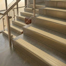 Brass stair nosings with ivory ribbed inserts on pale stone steps beside a glass balustrade