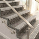 Raked back nosings with light grey ribbed inserts on mottled stone steps between stainless handrails