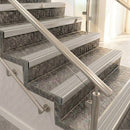 Raked back nosings with light grey ribbed inserts on mottled stone steps between stainless handrails
