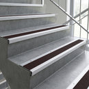 Dark brown carpet stair mats installed on concrete stairs with white metal rails and a glass railing.
