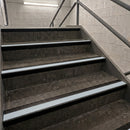Concrete stairs with metal handrails in an indoor stairwell, viewed from above at an angle.