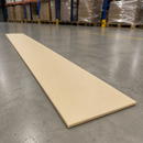 A long, rectangular light beige board or tile lies diagonally on a polished gray concrete warehouse floor, with pallets and shelving visible in the blurred background.