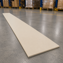 A long, narrow rectangular beige tile or board lies diagonally on a gray concrete warehouse floor, with pallets and shelving visible in the blurred background.