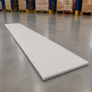 A long, rectangular white panel or board placed diagonally on a polished gray warehouse floor, with pallets and blue shelving visible in the blurred background.