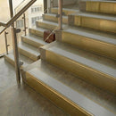 Brass stair nosings with smooth polar grey inserts on stone steps beside a glass balustrade