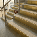Brass stair nosings with Portland stone castellated inserts on stone steps beside a glass balustrade