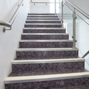 Long flight of dark marble-effect stairs edged with pale stone-coloured nosings and stainless handrails
