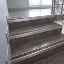 Concrete stairs with brushed stainless steel handrails and a thin wood accent strip along the nosing, shown in a modern interior setting.