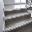 Gray concrete stair treads with silver metal rails and handrails on an indoor staircase.