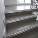 A set of modern concrete stairs with integrated stainless steel handrails and metal nosings, shown in a bright, minimalist interior.