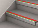 Red and green slimline insert stair nosings fitted to two pale grey steps