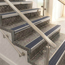 Raked back nosings with regency blue-grey ribbed inserts on mottled stone steps between stainless handrails