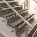 Raked back nosings with rustic brown ribbed inserts on mottled stone steps between stainless handrails