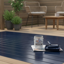 Dark navy blue anti-slip decking paint freshly applied to a garden timber deck with a paint roller and tin resting on the boards